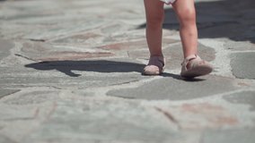 Baby legs with sandals on patterned paving tiles, cement brick floor, slow motion - Powered by Shutterstock - Get 15% off with code: PIKWIZARD15