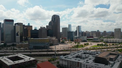 Panoramic aerial view of downtown skyscrapers behind rush highway. Tall modern office building panning footage from drone. Dallas, Texas, US in 2021
