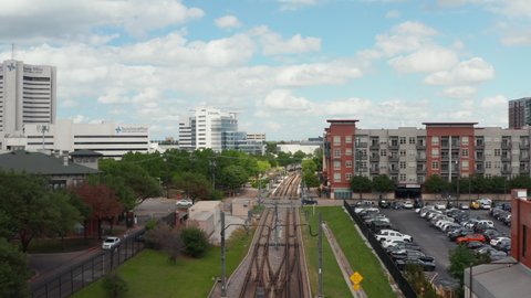 Aerial view of empty double-track railway line leading through town. Cars driving on rail crossing. Forward flying drone. Dallas, Texas, US in 2021