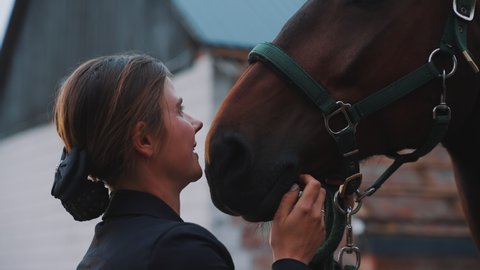 Beautiful young girl kissing her seal brown horse. Stroking and expressing her love for the horse. Bonding between horse and its owner. Love for horses. 