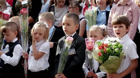 little boy yawns. child at school with a bouquet of flowers at the celebratory event knowledge day september 1: Gomel, Belarus - 09.01.2020