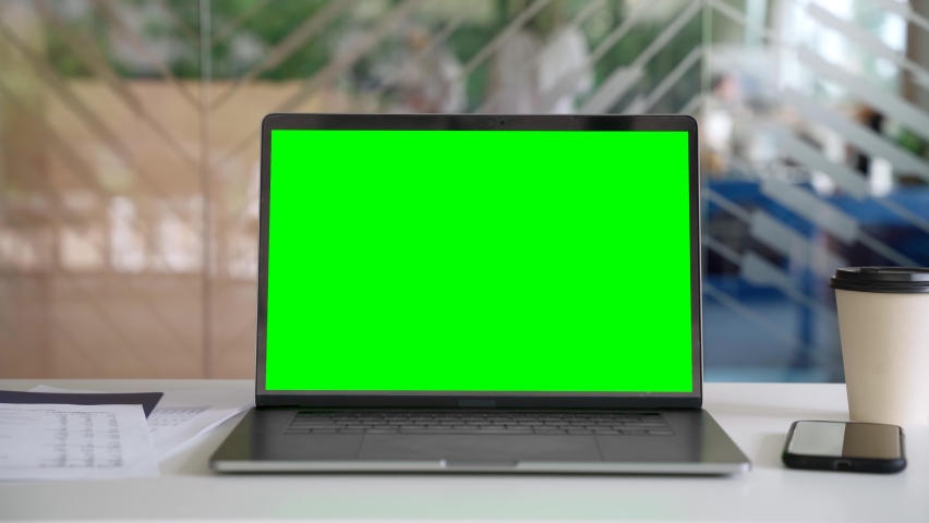 Workplace with laptop computer on desk with blank empty green mockup screen for advertising standing in modern contemporary office. Business software website ads technology concept. | Shutterstock HD Video #1075373738