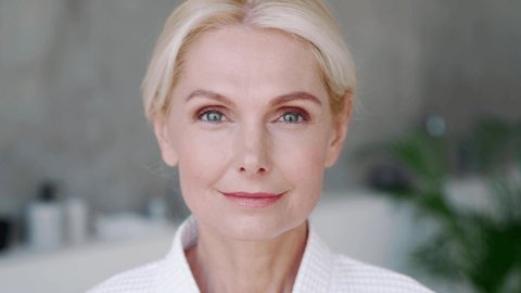 Closeup portrait of attractive middle aged blond woman wearing bathrobe with natural makeup looking at camera. Advertising of perfect antiage skin care products, hotel spa services concept.