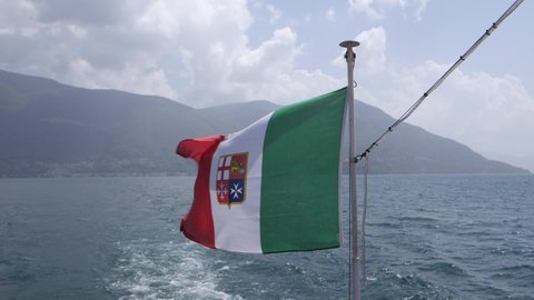 Italian flag waving in the wind in front of a big mountain in the lake maggiore