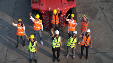 top view of Containers worker standing  excited and raised hand up to success in morning meeting  . group of labor clapping hand to celebrate at warehouse logistic in Cargo freight aerial view 