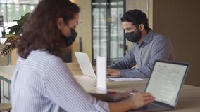Indian business man student wearing face mask working on laptop safe distancing. Diverse people in facemasks using computers sitting at table with social distance sign in office coworking or campus. - Powered by Shutterstock - Get 15% off with code: PIKWIZARD15