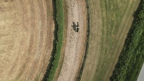 Aerial top down view of horse and rider walking slowly on the race track one hot summer day at the swedish countryside . 4K video, slowmotion x 2, stabilized footage. Birds eye of horse shadows.
