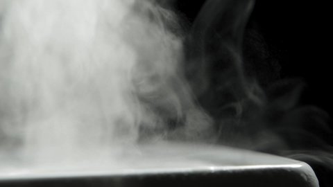 Steam from a steam generator close-up. Thick white smoke on a black background.