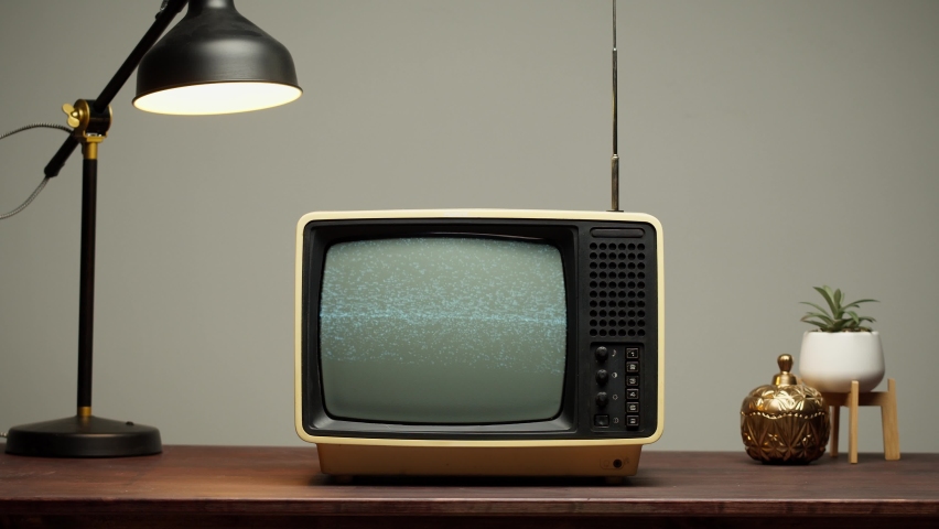Old retro television with antenna on grey background. Broken old-fashioned TV screen with ripples on table, bad signal reception, cinematography concept.