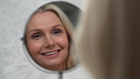 Happy 50s middle aged woman model touching face skin looking in mirror reflection. Smiling mature old lady pampering, healthy moisturized skin care, aging beauty, skincare treatment cosmetics concept. - Powered by Shutterstock - Get 15% off with code: PIKWIZARD15