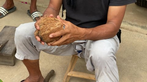 Man breaking raw coconut from hammer