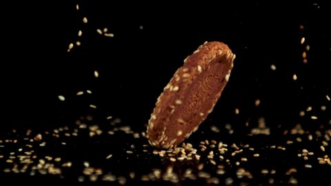 Super slow motion oatmeal cookie falls on the table with sesame seeds. On a black background.Filmed on a high-speed camera at 1000 fps.