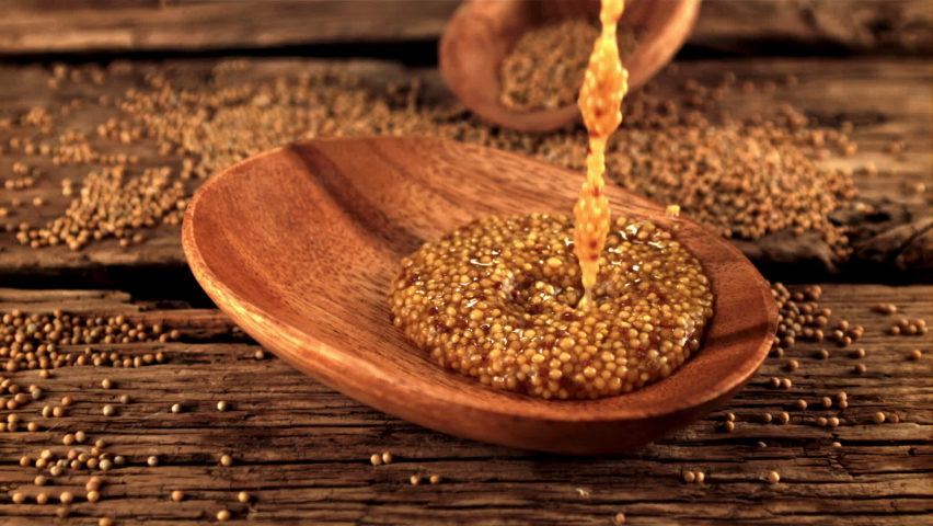 Super slow motion in a wooden plate drops fresh mustard. On a wooden background. Filmed on a high-speed camera at 1000 fps.