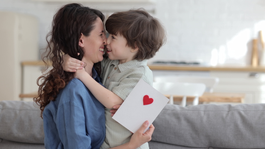 Cute preschool son congratulating young mom with mother day, valentine day or birthday give mommy handmade postcard with red heart. Loving mum and kid cuddling embrace cheerful to family holiday event Royalty-Free Stock Footage #1075391144