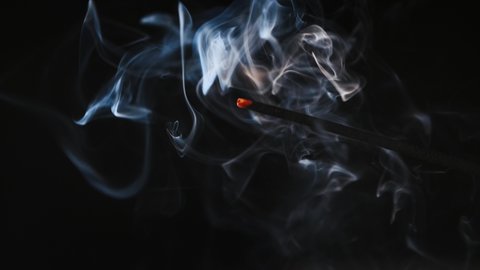 A man hand holds a lighter that sets fire to an aroma stick. Smoldering incense chinese stick fills a room with a smell of frankincense. Just inhale the fragrance and relax. fire enforces effect of it