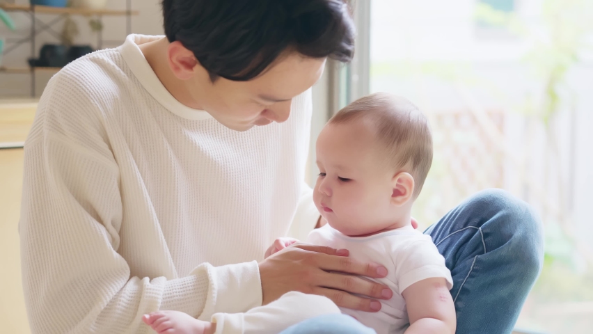 Asian man fondling pretty baby in the room. Child rearing concept. Royalty-Free Stock Footage #1075402913