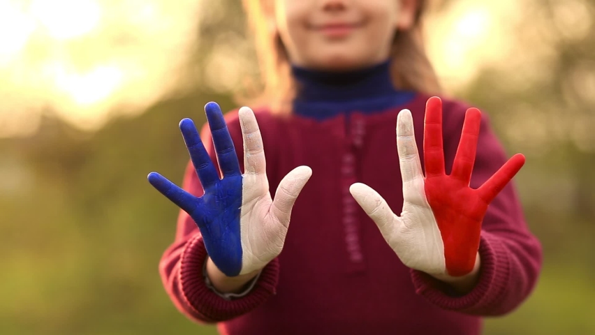 Love and happiness concept. Cute child forming heart gesture with hands outdoors on nature sunset bokeh background. Heart shape of kids hand painted in france flag colors, kids body language Royalty-Free Stock Footage #1075407230