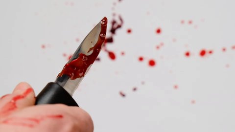 Bloody knife.Sharp knife with  blood drips in a man's hand  on a white background with drops of blood.Crime and murder concept.