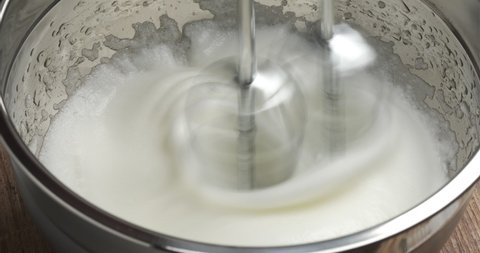 Electric mixer whips egg whites into fluffy cream