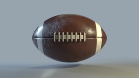 Side on view of a 3D American Football spinning on the spot. Standard football in a continuous roll perfect for sports advertising. 4K clip at 30fps for smooth motion with a luma matte.