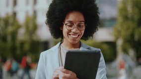 Portrait of cheerful african black beautiful woman holding tablet using computer device and smiling satisfied to camera. Businesswoman. Attractive female face.