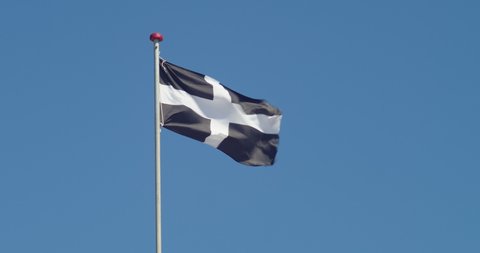 Cornwall Flag - Saint Piran's Flag On Pole Waving In The Wind With Blue Sky In The Background. - wide shot