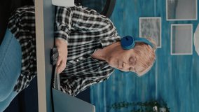 Vertical video: Happy old woman entrepreneur with headset listening music while checking statistics, writing on laptop working from home. Retired worker using modern technology reading typing - Powered by Shutterstock - Get 15% off with code: PIKWIZARD15