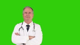 Mature doctor with his stethoscope looking at the camera against a green screen, Healthcare workers in the Coronavirus Covid19 pandemic