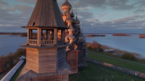 Kizhi wooden church complex Karelia best traditional style old landmark on island at orange sunset. Flight near belfry next to bell tower. Russia historical heritage chapel. Bell tower tample. Aerial
