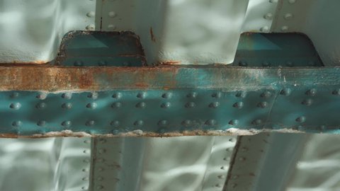 Water reflections on the underside of a rusty blue iron bridge