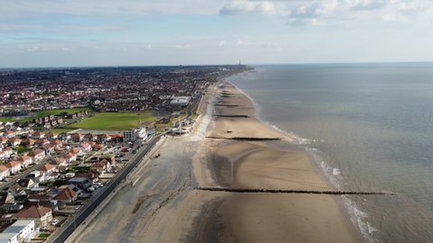 Drone footage high above the sandy beach and the crashing waves at Cleveleys Lancashire with Blackpool in the far distance. 