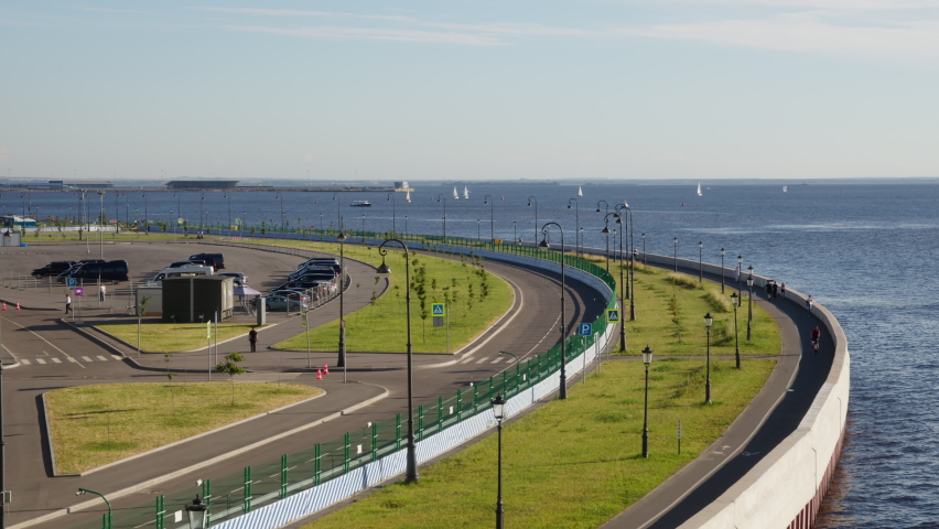 seaside promenade with walking people, bike paths and green grass.