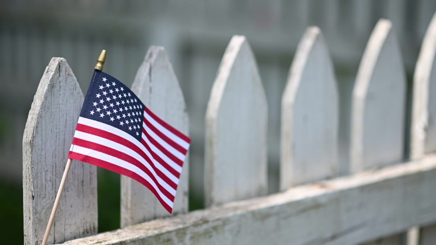 American flag waving in the wind on white picket fence for US holidays