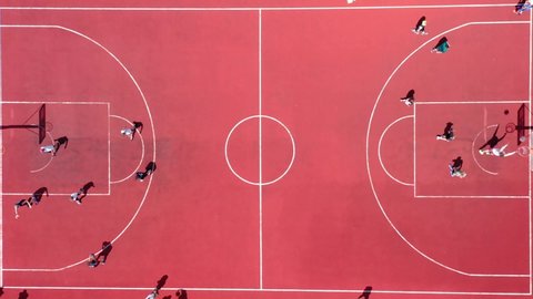 Aerial view of young athletes playing street basketball on an open summer playground. Sports teams compete in a basketball match in the same ring.