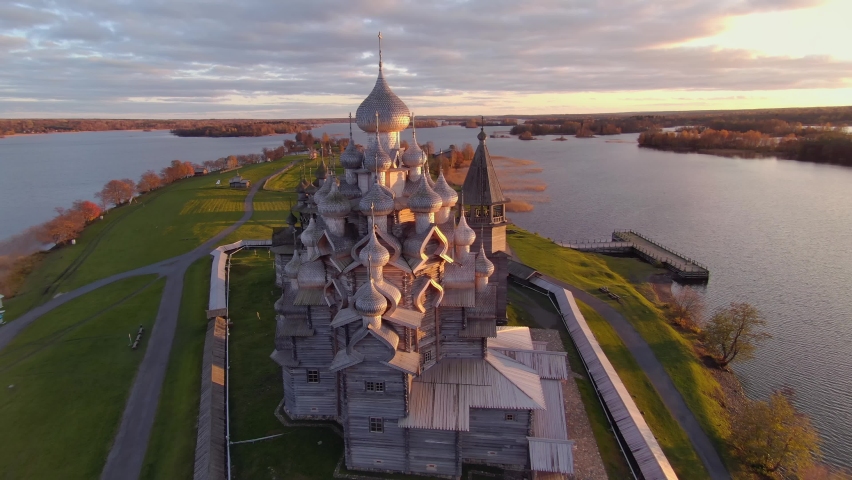 From great height beautiful Kizhi wooden church complex on island lake at cinematic sunset. Karelia historical landmark. Russia average strip traditional style medieval heritage. Golden ring. Horizon  Royalty-Free Stock Footage #1075441586