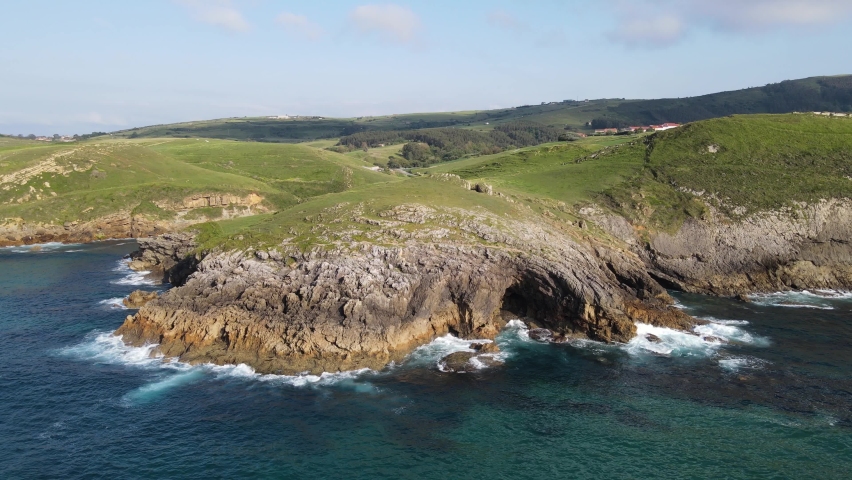 Panoramic of marine reef with caves in the rocks and ocean waves.