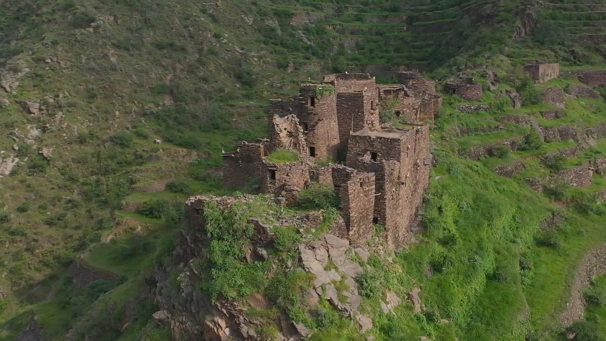 An old stone lookout fort amongst the houses built on the sides of the mountains in the historical Faifa region of Saudi Arabia (aerial view) Al Dayer Jizan Region, Saudi Arabia. | Shutterstock HD Video #1075448315
