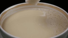 slow motion of a close up shot of a sugar cube dropping into a cup of milky tea - Powered by Shutterstock - Get 15% off with code: PIKWIZARD15