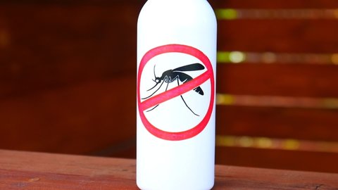 Close-up of a spray bottle with the anti mosquito sign on it against wooden background