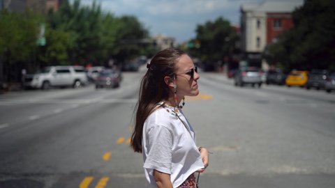 Young woman casually crossing the street of a small town - portrait view