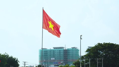 A Vietnamese flag behind the blue sky long shot. Ho Chi Minh Vietnam. This is in center of Phan rang's national building behind the sky in Ho Chi Minh Vietnam.