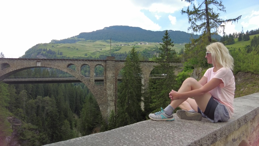 Woman looks Solis Viaduct bridge of Swiss railway in Switzerland. Swiss train Bernina and World Heritage in Grisons. Albula Railway section between Thusis and Tiefencaste