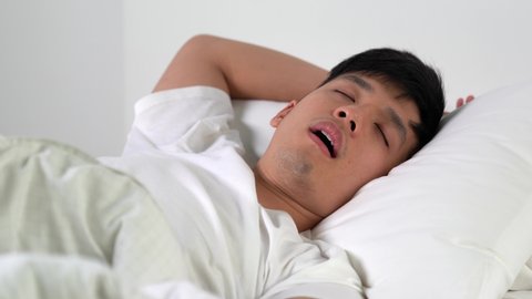 Young Asian man snoring While sleeping in bed.