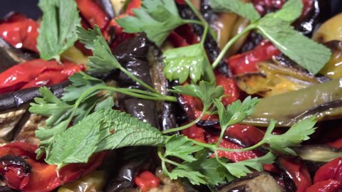 A dish of red and green pepper, eggplant, baked in the oven and decorated with parsley macro shot