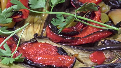 A dish of red and green pepper, eggplant, baked in the oven and decorated with parsley macro shot