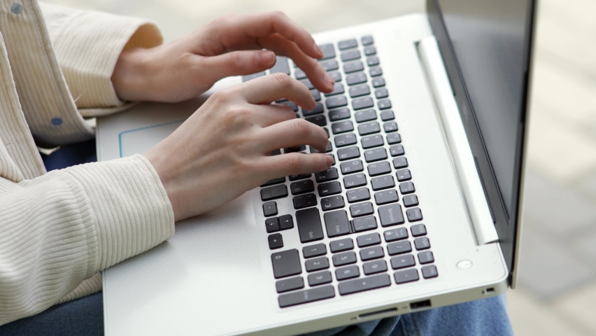 A woman is typing text on a laptop keyboard close-up. Female hands are typing on the keyboard. Business and office work concept. Royalty-Free Stock Footage #1075469903
