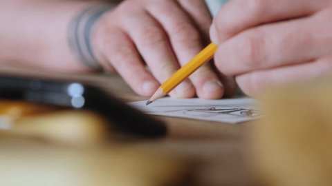 The artist makes a sketch on a piece of paper. Close-up of a hand with a pencil. wood carver draws a sketch for wood carving. robot head sketch