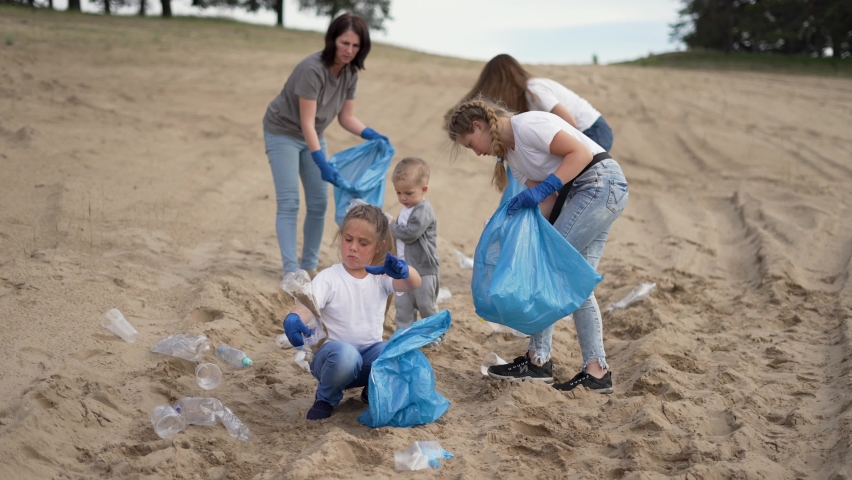 Family cleaning up plastic trash. People are eliminating environmental problem. People at garbage dump. Family cleaning up plastic trash on beach. Environmental problem with plastic. Polluted beach Royalty-Free Stock Footage #1075476446