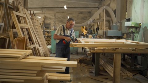 A Worker is crafting the wooden items at the Industrial manufacturing facility. The manufacture of crafted wooden products. The manufacture of handcrafted wooden windows. Production Process. Factory.