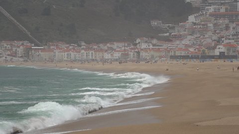 NAZARE, PORTUGAL – 12 JUNE 2021: Powerful waves crash on shores of Nazare, a popular beach holiday town and surf spot in Portugal
